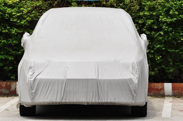 small car parked in a parking lot with a white tarp covering